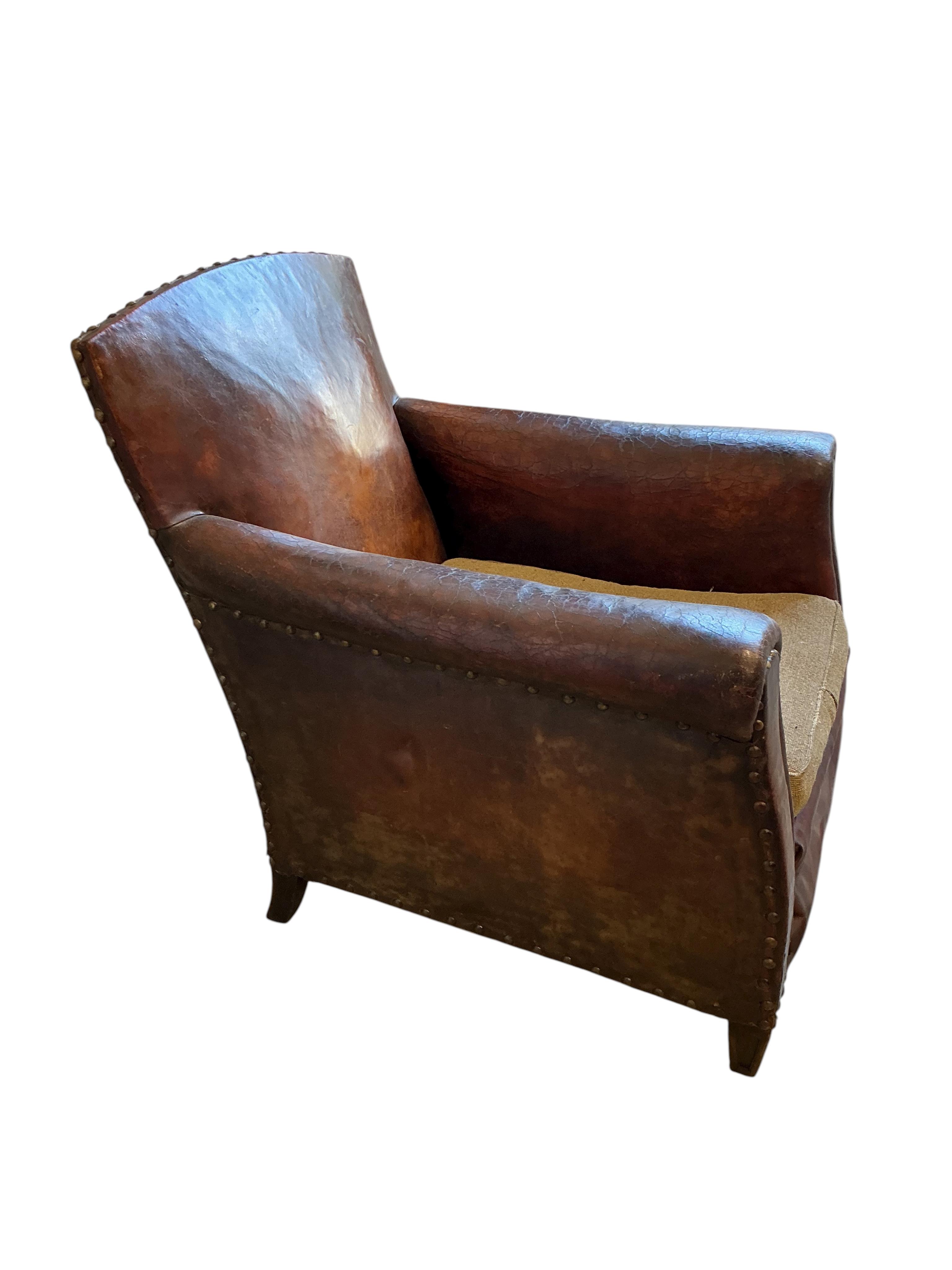 A near pair of early 20th century studded brown leather club chairs, width 79cm, depth 86cm, height 89cm